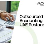 Accountant reviewing a ledger and restaurant receipts on a wooden desk in a UAE cafe, highlighting outsourced accounting for hospitality finance management.
